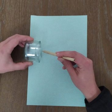 Repérer sur la feuille de papier, avec un crayon, la hauteur du pot de yaourt. Tracer une ligne du haut au bas de la feuille.